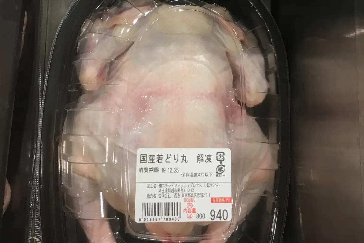 Whole raw chicken in a sealed retail tray with a printed label